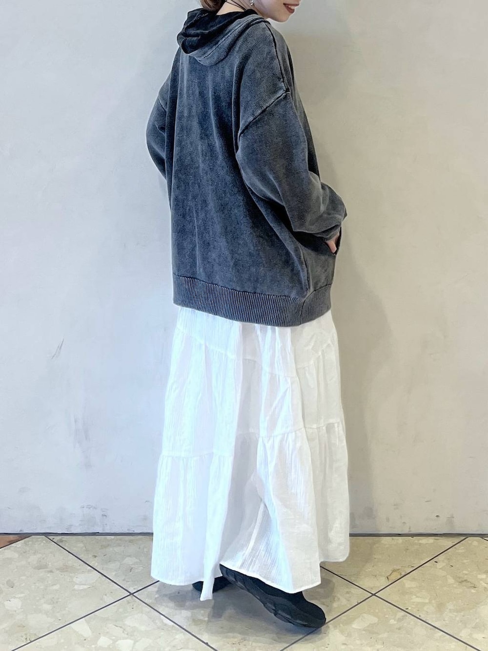 ブラック系のスニーカー、グレー系のパーカー、ホワイト系のスカートを着用したレディースの冬コーディネートの2枚目の写真