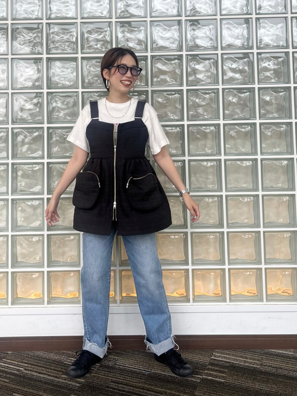 ブルー系のデニムパンツ、ブラック系のベスト、ホワイト系のTシャツ/カットソーを着用したレディースの夏コーディネートの2枚目の写真