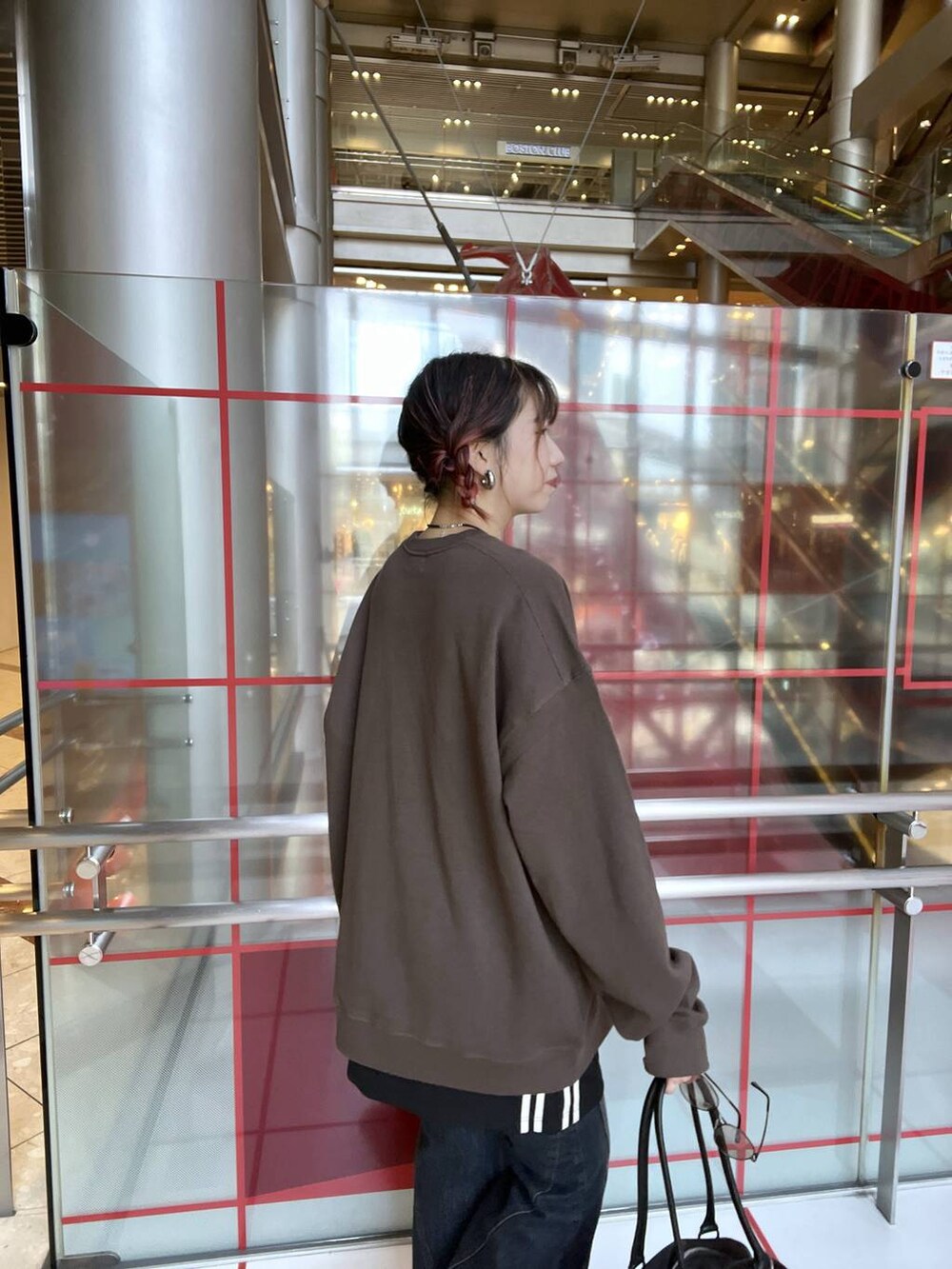 ブルー系のデニムパンツ、ブラック系のスカート、ブラック系のボストンバッグを着用したレディースの秋コーディネートの3枚目の写真