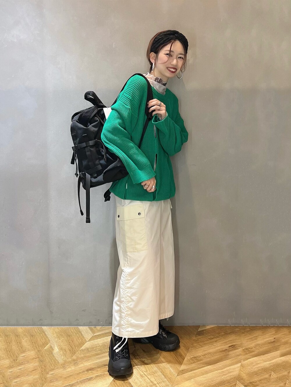 ブラック系のブーツ、ホワイト系のスカート、グリーン系のニット/セーターを着用したレディースの冬コーディネートの2枚目の写真