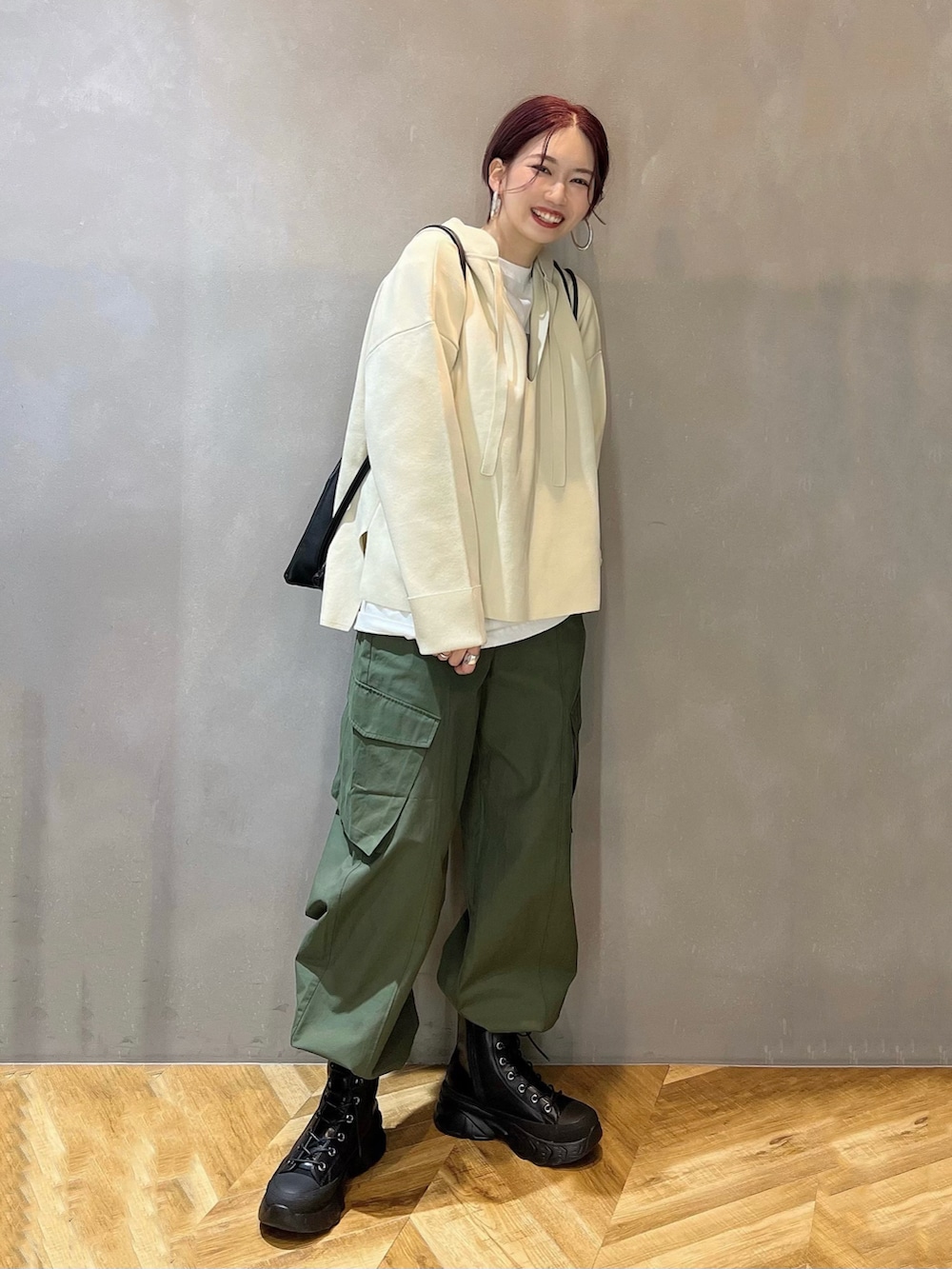 ブラック系のブーツ、グリーン系のカーゴパンツ、ホワイト系のニット/セーターを着用したレディースの冬コーディネートの2枚目の写真