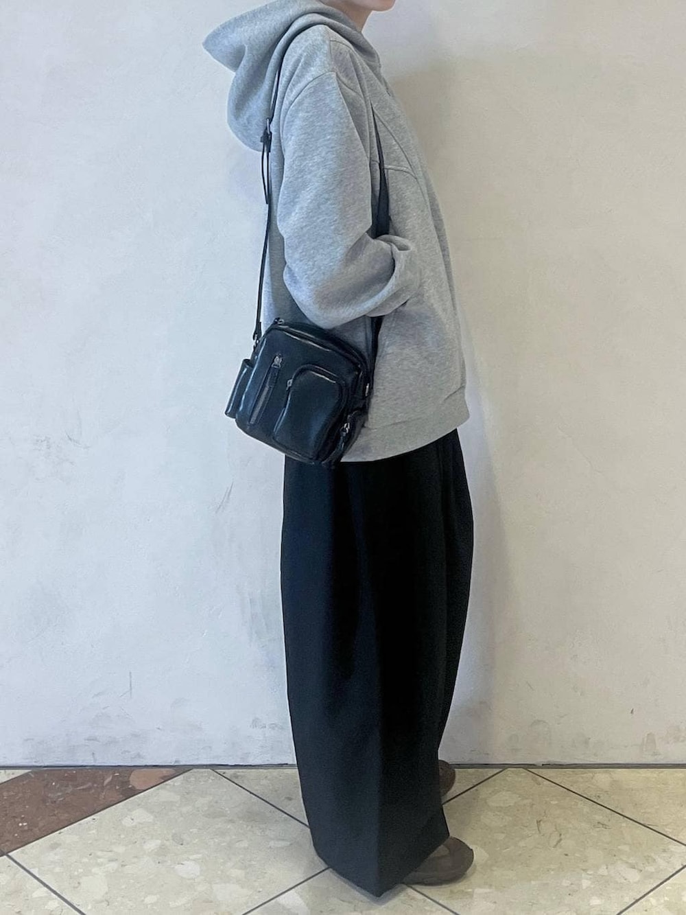 グレー系のパーカー、ブラウン系のスニーカー、ブラック系のスラックスを着用したレディースの春コーディネートの2枚目の写真