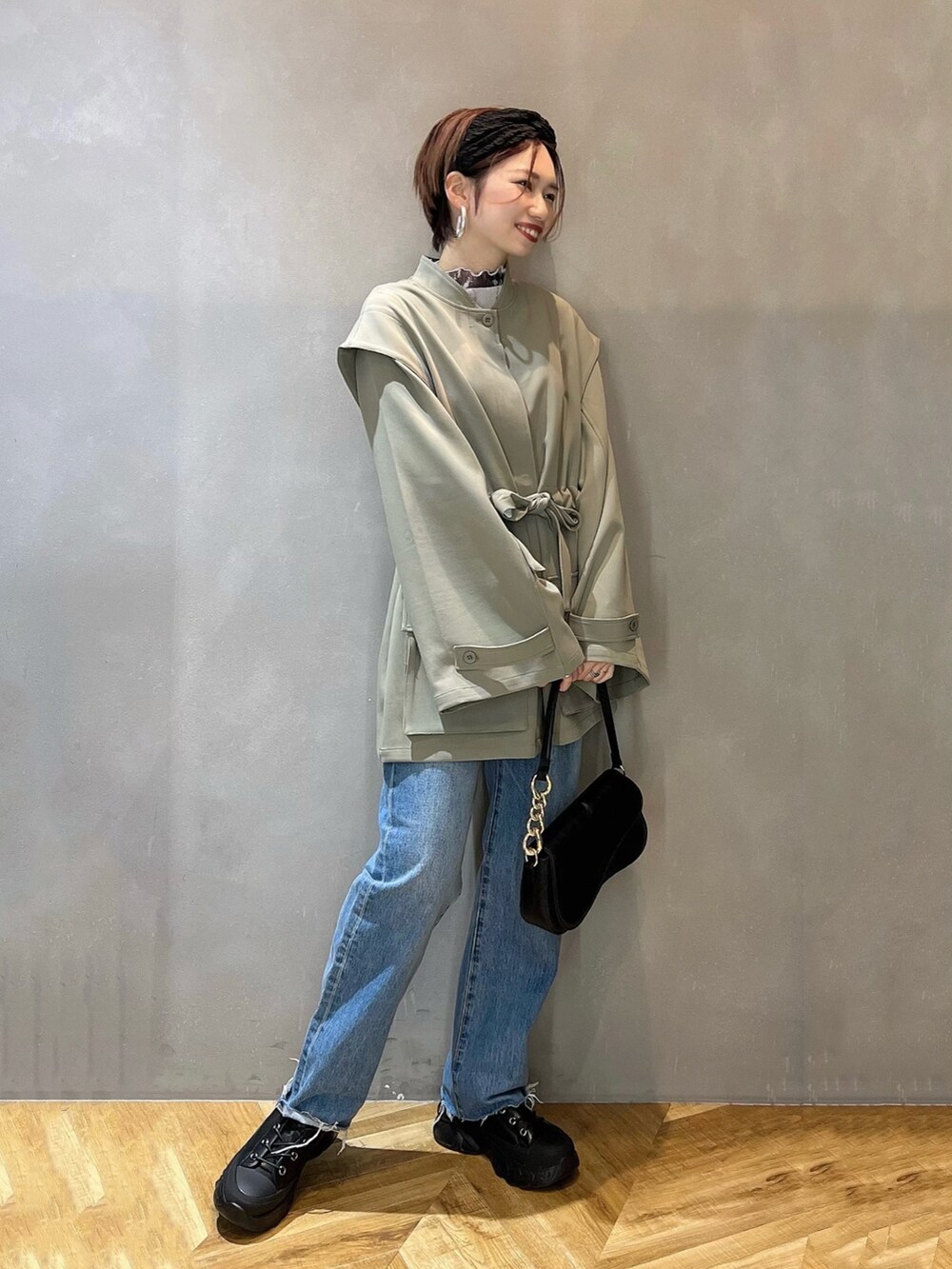 ブルー系のデニムパンツ、ブラック系のショルダーバッグ、ブラック系のブーツを着用したレディースの冬コーディネートの3枚目の写真