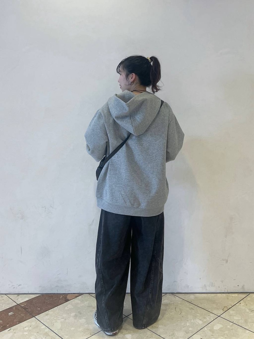 グレー系のパーカー、ブラック系のデニムパンツ、ブラック系のショルダーバッグを着用したレディースの春コーディネートの3枚目の写真