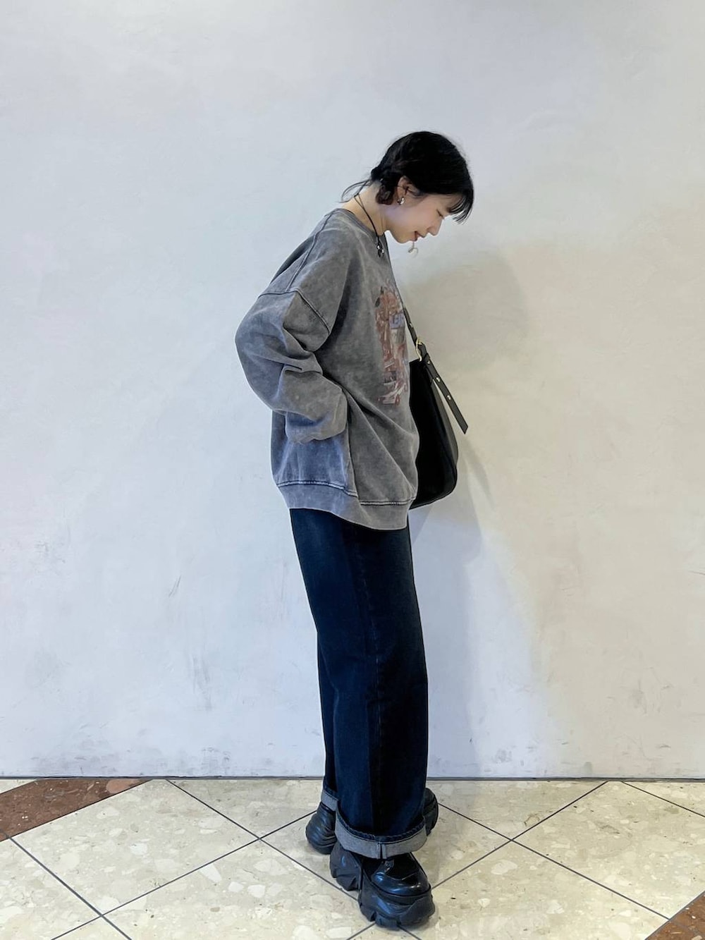 ブラック系のブーツ、ブラック系のショルダーバッグ、ブルー系のスラックスを着用したレディースの冬コーディネートの2枚目の写真