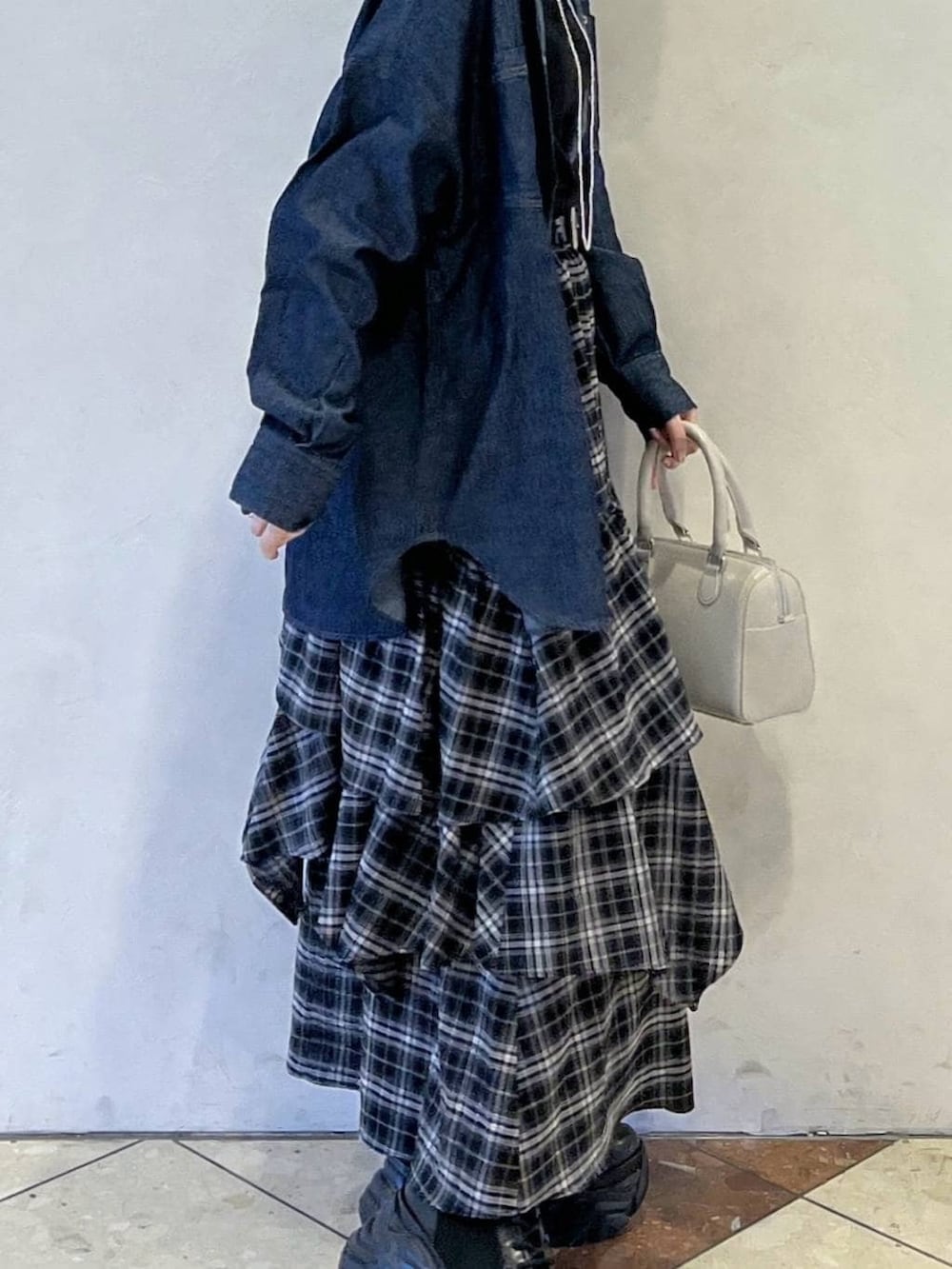 ブラック系のブーツ、ブラック系のスカート、ホワイト系のボストンバッグを着用したレディースの冬コーディネートの2枚目の写真