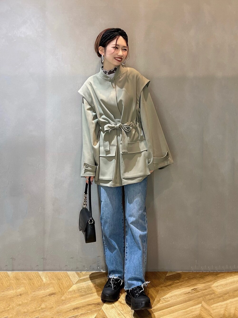 ブルー系のデニムパンツ、ブラック系のショルダーバッグ、ブラック系のブーツを着用したレディースの冬コーディネートの2枚目の写真