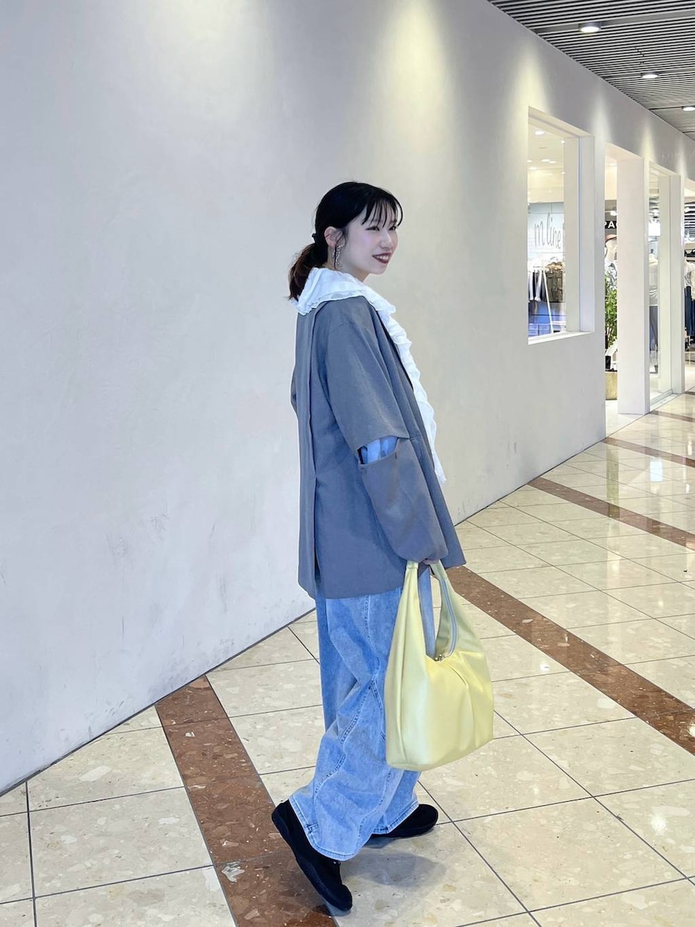 ブラック系のスニーカー、イエロー系のトートバッグ、グレー系のテーラードジャケットを着用したレディースの春コーディネートの2枚目の写真