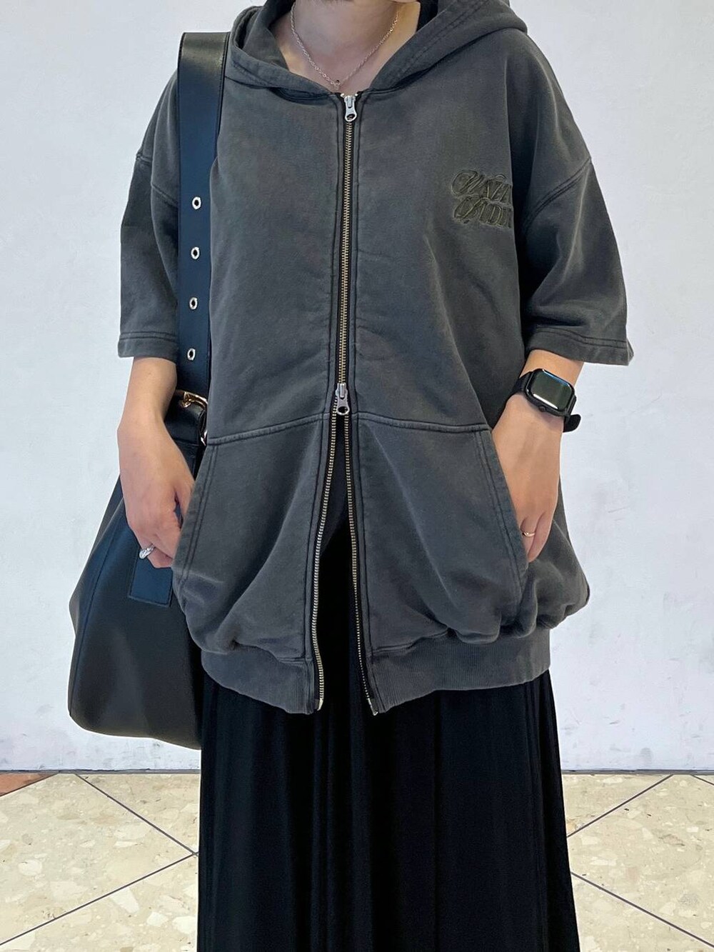 ブラック系のショルダーバッグ、ブラック系のスカート、グレー系のパーカーを着用したレディースの夏コーディネートの3枚目の写真