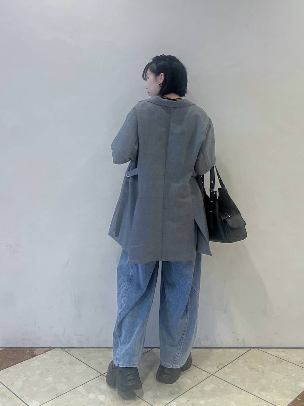 ブラック系のスニーカー、ブルー系のデニムパンツ、グレー系のテーラードジャケットを着用したレディースの春コーディネートの3枚目の写真