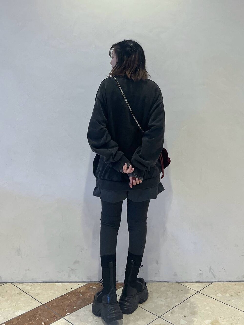 ブラック系のブーツ、グレー系のスウェット、レッド系のハンドバッグを着用したレディースの冬コーディネートの2枚目の写真