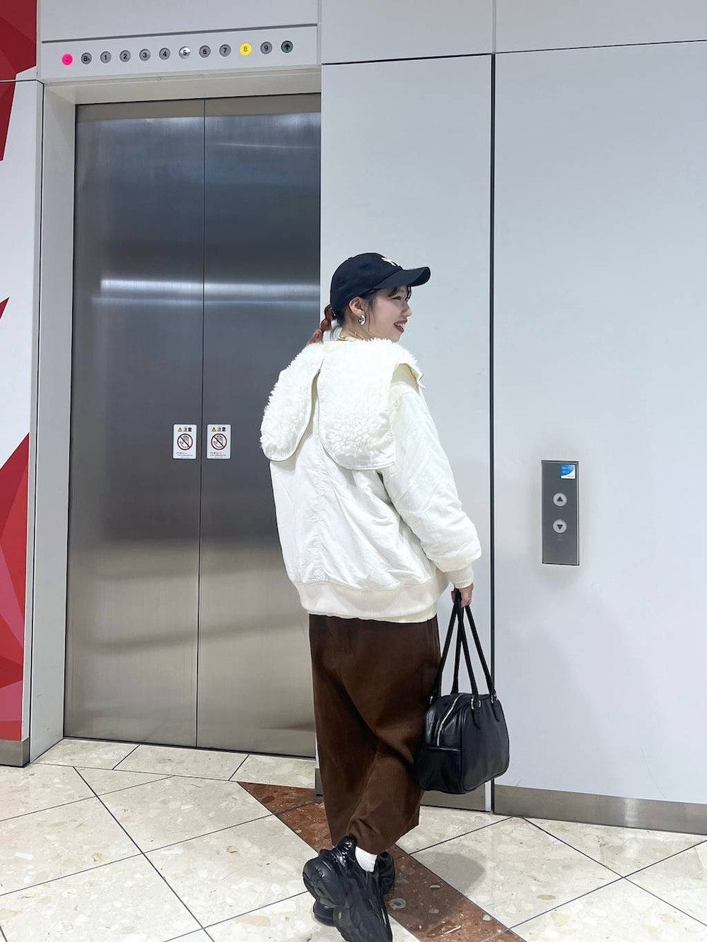 ブラック系のスニーカー、ホワイト系のブルゾン、ブラック系のボストンバッグを着用したレディースの秋コーディネートの4枚目の写真