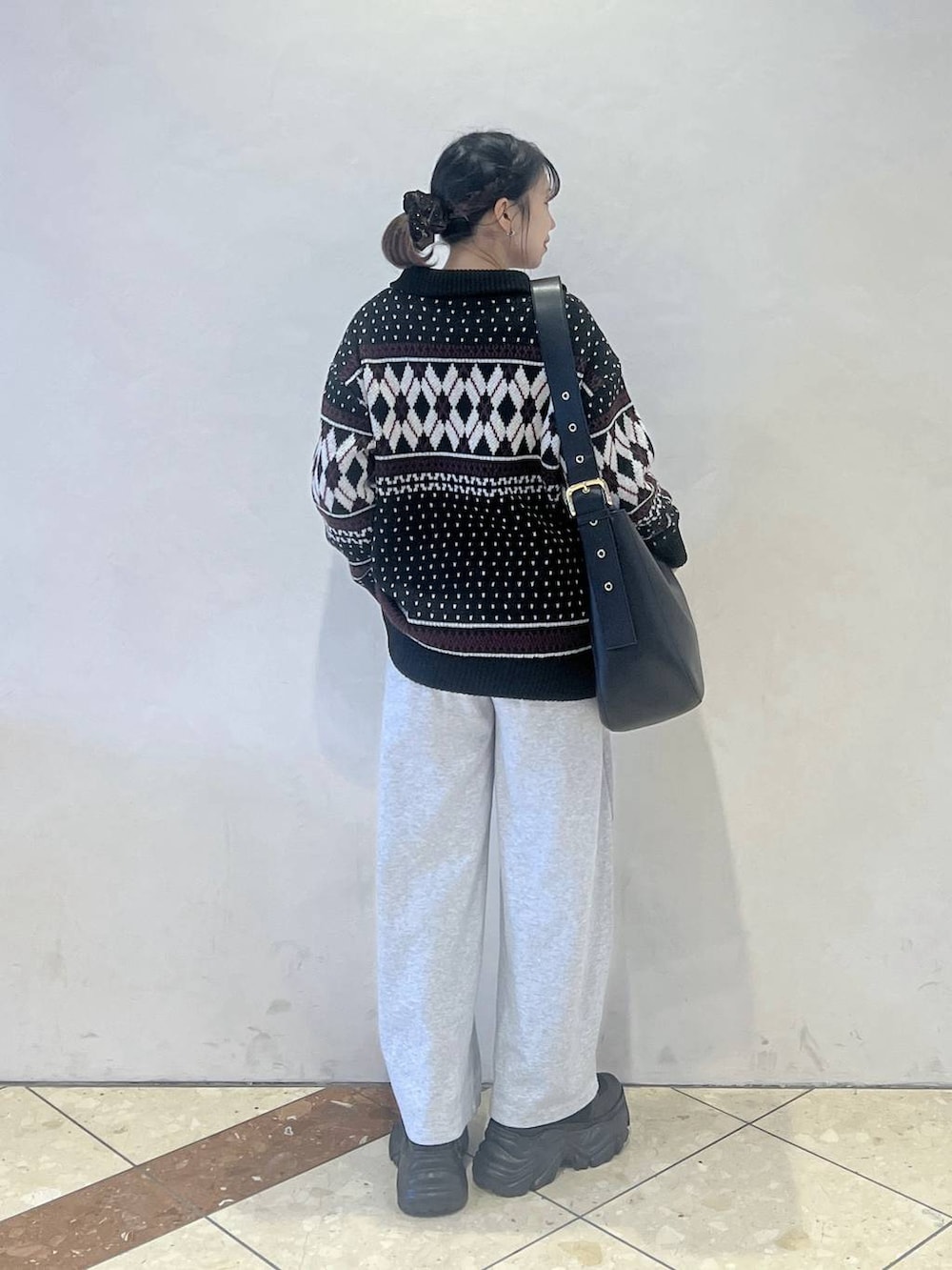ブラック系のブーツ、ブラック系のショルダーバッグ、グレー系のスウェットパンツを着用したレディースの冬コーディネートの4枚目の写真