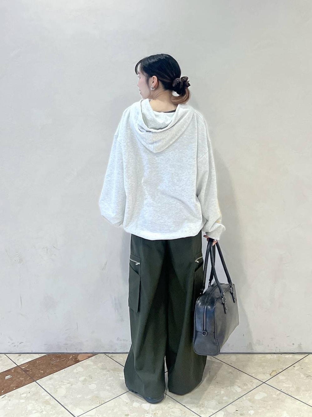 ブラック系のボストンバッグ、グリーン系のスラックス、グレー系のパーカーを着用したレディースの春コーディネートの3枚目の写真