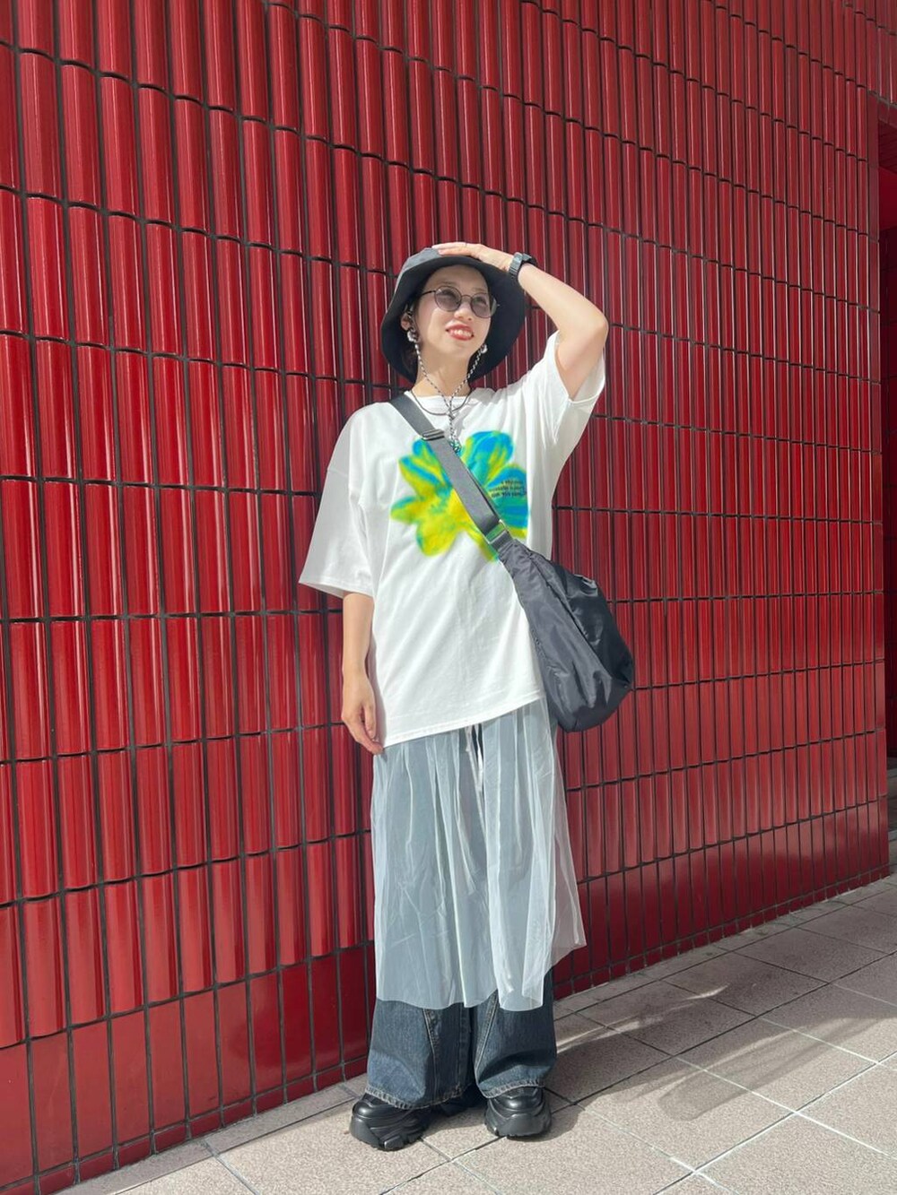 ブラック系のスニーカー、ブラック系のショルダーバッグ、ブルー系のデニムパンツを着用したレディースの夏コーディネートの2枚目の写真