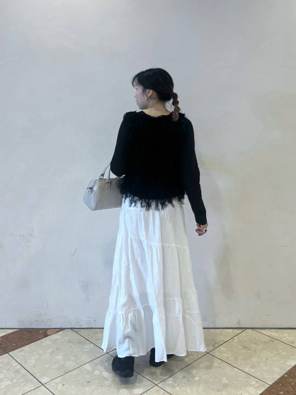 ホワイト系のボストンバッグ、ブラック系のスニーカー、ブラック系のベストを着用したレディースの冬コーディネートの2枚目の写真