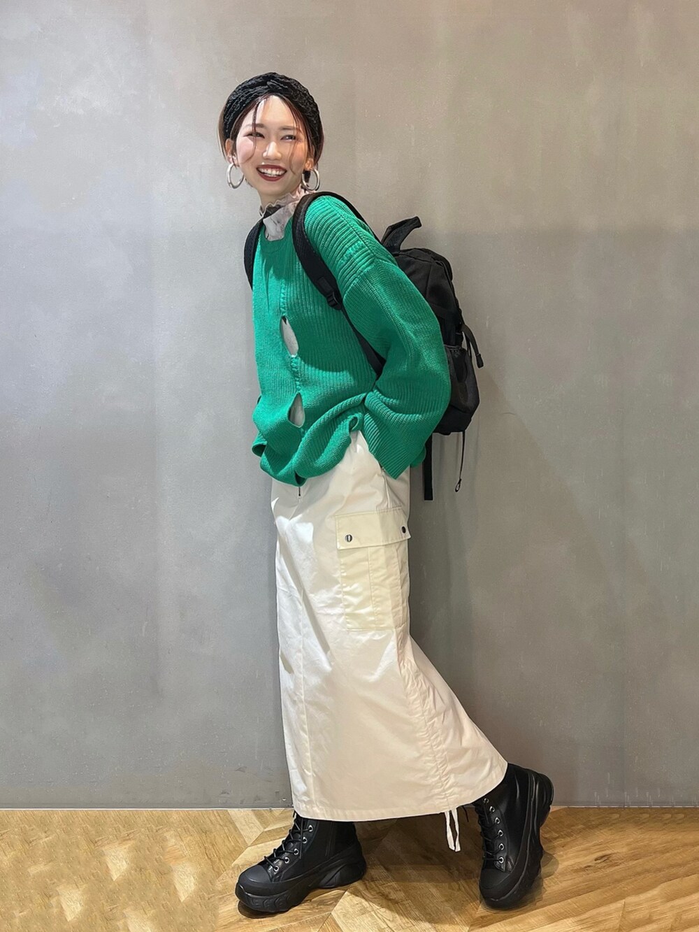 ブラック系のブーツ、ホワイト系のスカート、グリーン系のニット/セーターを着用したレディースの冬コーディネートの3枚目の写真