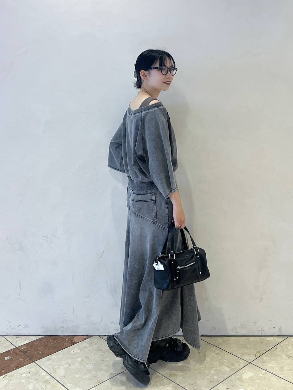 ブラック系のショルダーバッグ、グレー系のTシャツ/カットソー、グレー系のデニムスカートを着用したレディースの夏コーディネートの3枚目の写真