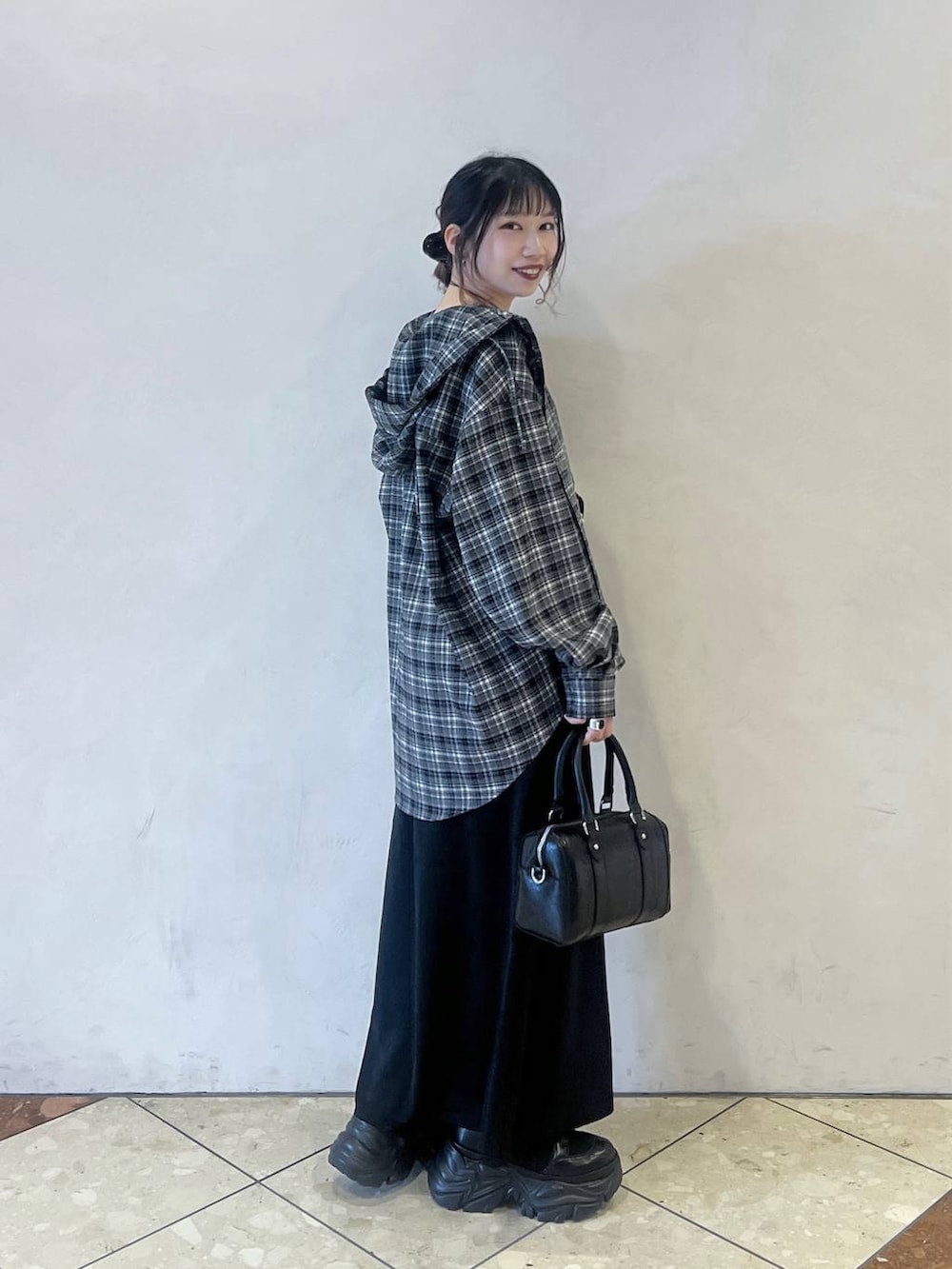 ブラック系のブーツ、ブラック系のスカート、ブラック系のボストンバッグを着用したレディースの冬コーディネートの2枚目の写真