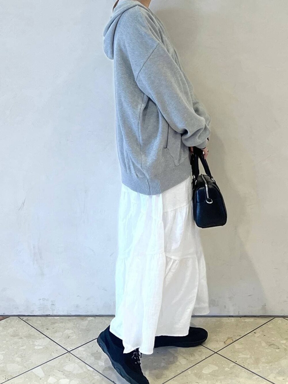 ブラック系のボストンバッグ、ブラック系のスニーカー、グレー系のパーカーを着用したレディースの春コーディネートの2枚目の写真