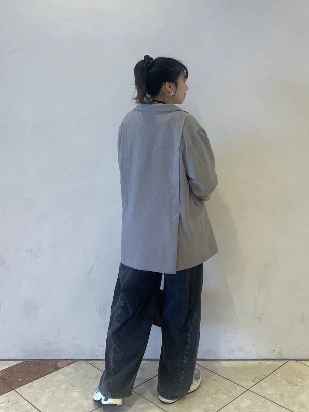 ベージュ系のテーラードジャケット、ブラック系のデニムパンツ、グレー系のショルダーバッグを着用したレディースの春コーディネートの2枚目の写真