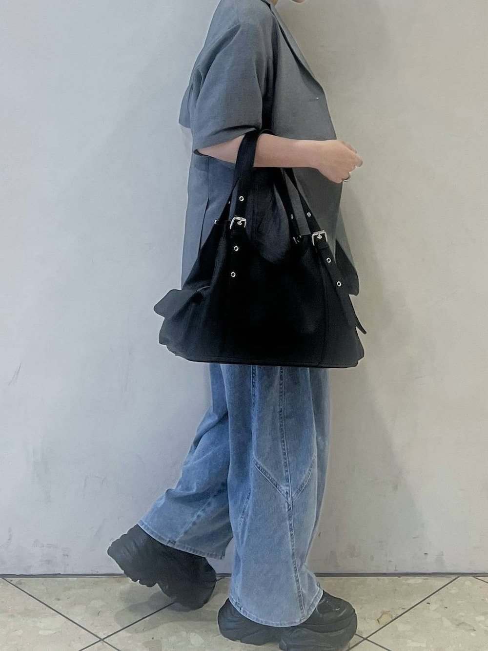 ブラック系のスニーカー、ブルー系のデニムパンツ、グレー系のテーラードジャケットを着用したレディースの春コーディネートの2枚目の写真