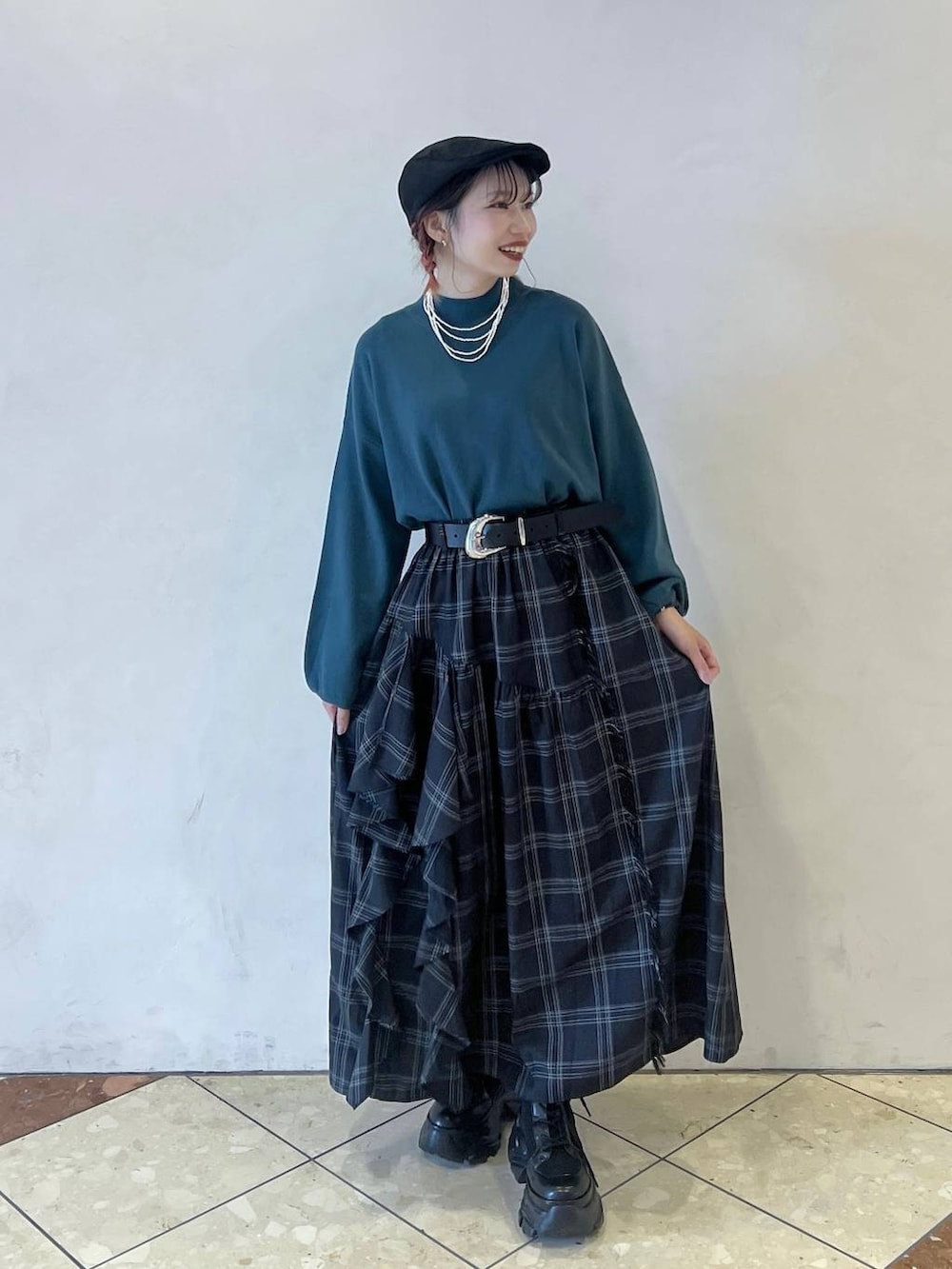 ブラック系のブーツ、グリーン系のニット/セーター、ブラック系のスカートを着用したレディースの秋コーディネートの2枚目の写真