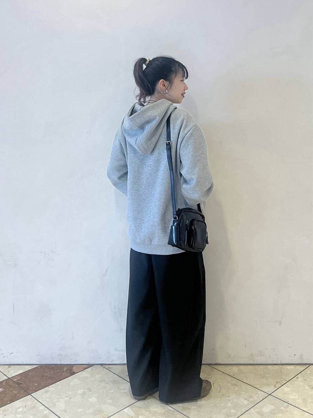 グレー系のパーカー、ブラウン系のスニーカー、ブラック系のスラックスを着用したレディースの春コーディネートの3枚目の写真