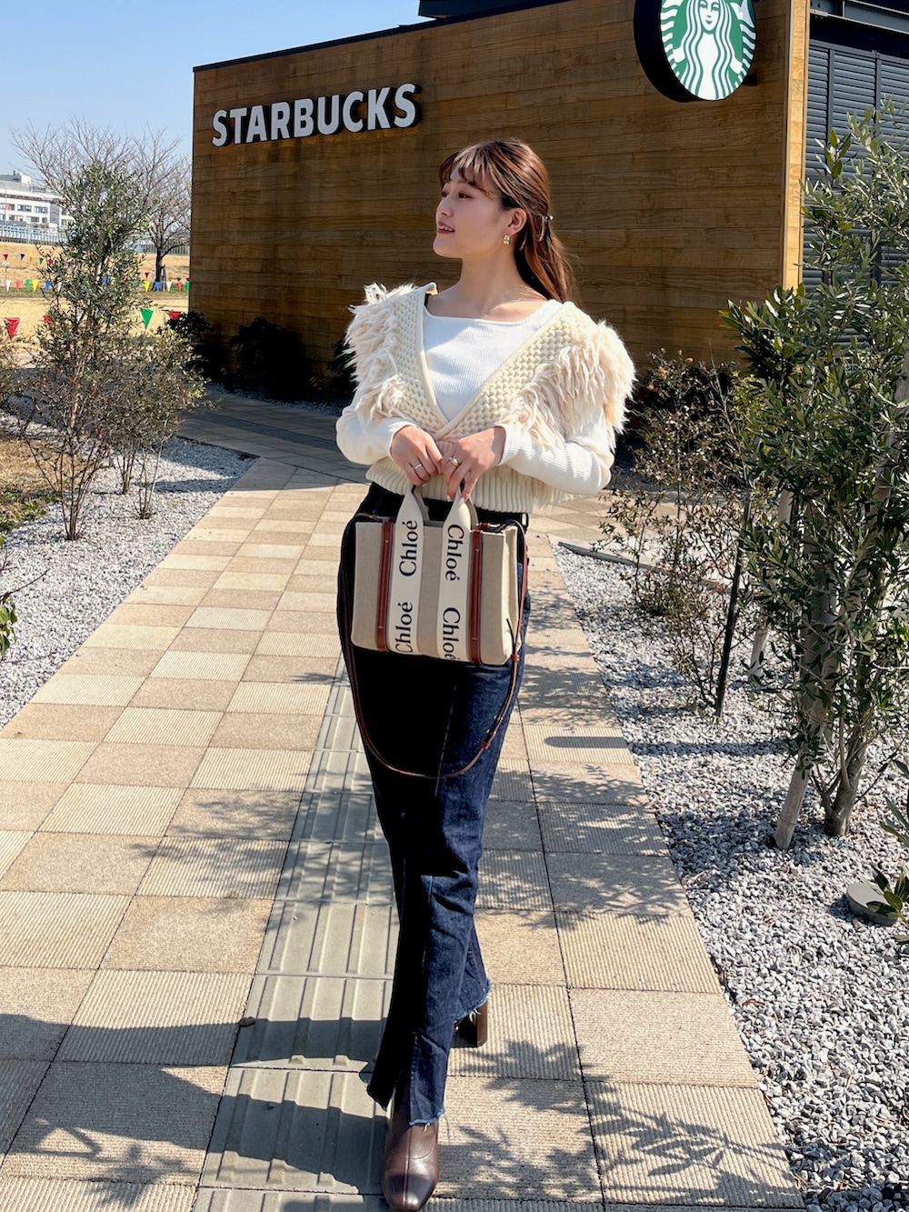 ブルー系のデニムパンツ、ホワイト系のTシャツ/カットソー、ホワイト系のニット/セーターを着用したレディースの春コーディネートの2枚目の写真