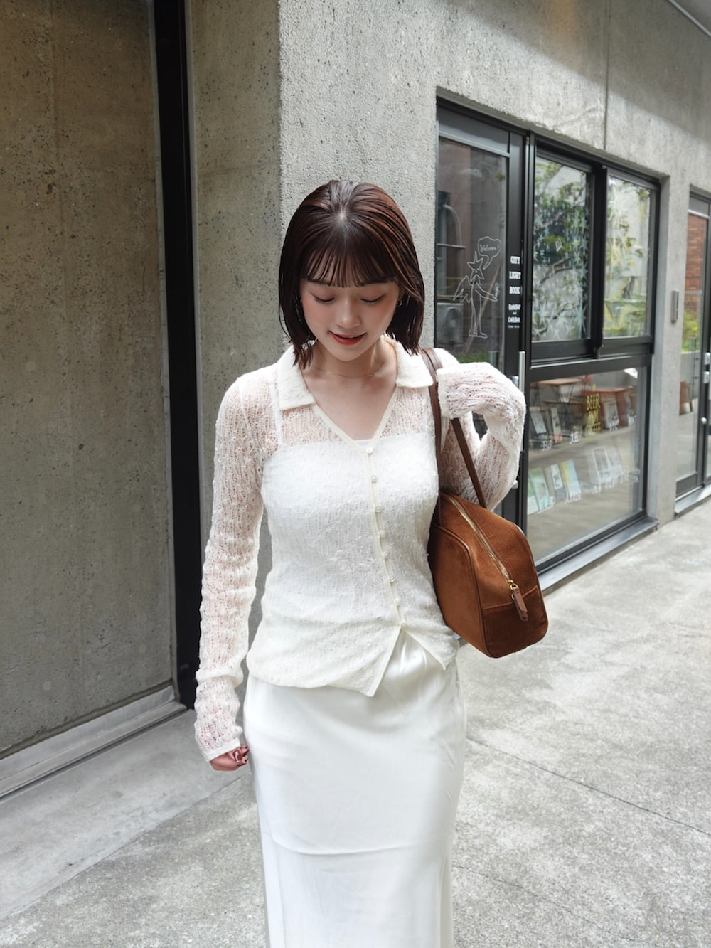 ホワイト系のスカート、ホワイト系のポロシャツ、ブラウン系のトートバッグを着用したレディースの秋コーディネートの2枚目の写真