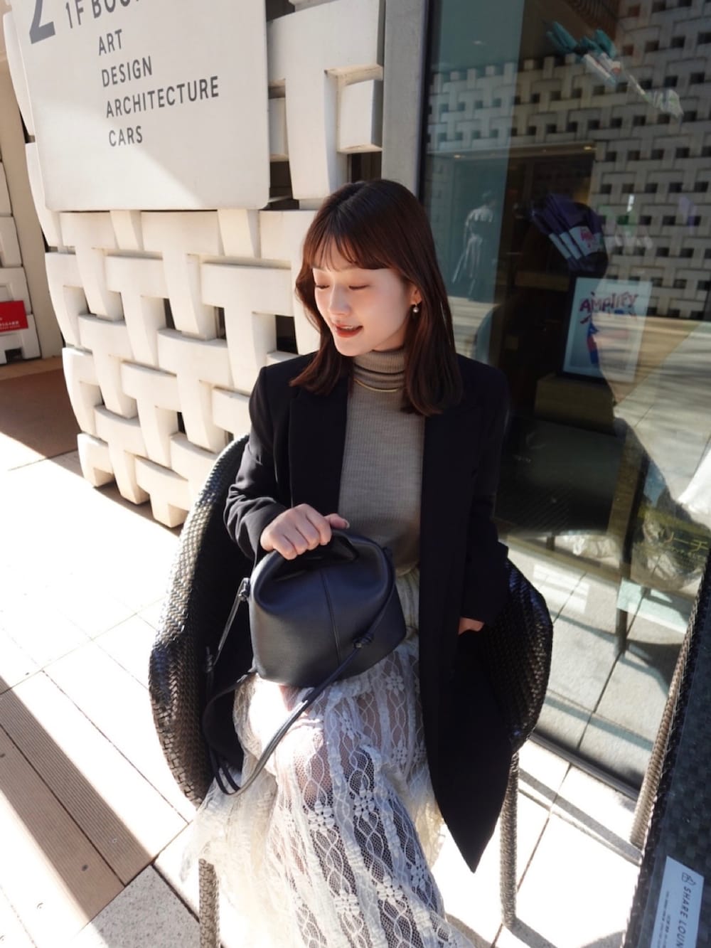 ブラック系のテーラードジャケット、ホワイト系のスカート、ブラウン系のブーツを着用したレディースの秋コーディネートの2枚目の写真