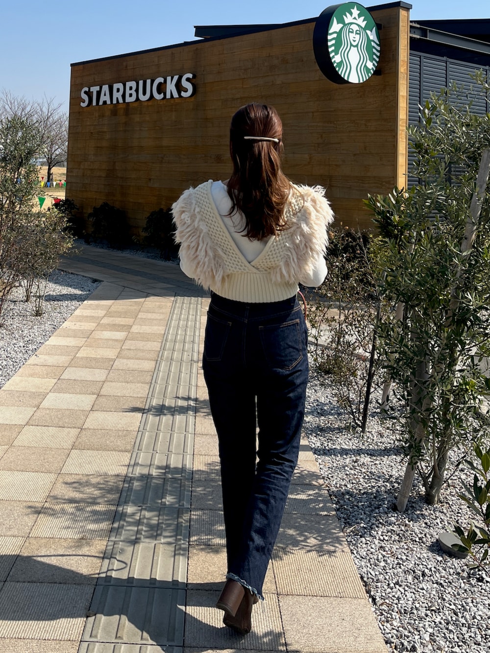 ブルー系のデニムパンツ、ホワイト系のTシャツ/カットソー、ホワイト系のニット/セーターを着用したレディースの春コーディネートの3枚目の写真