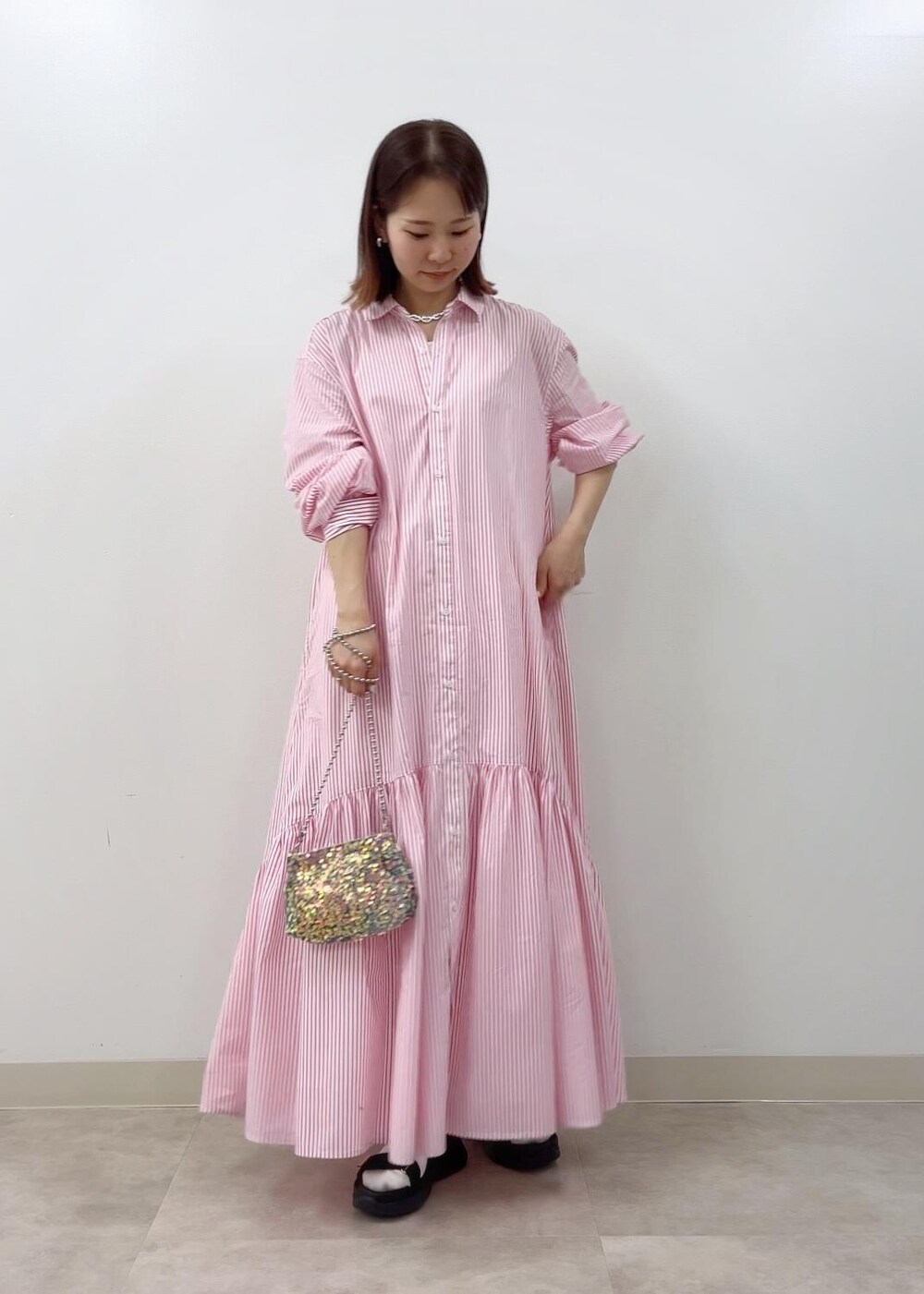 ブラック系のサンダル、グレー系のショルダーバッグ、ピンク系のシャツワンピースを着用したレディースの春コーディネートの2枚目の写真