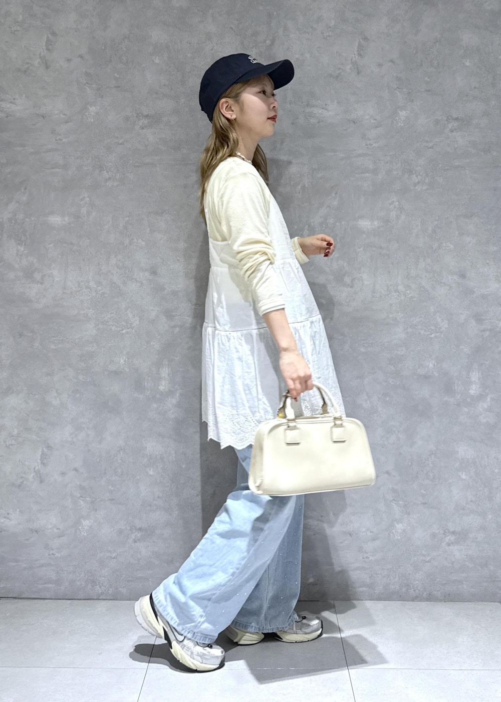 ブルー系のデニムパンツ、ホワイト系のボストンバッグ、ベージュ系のTシャツ/カットソーを着用したレディースの春コーディネートの9枚目の写真