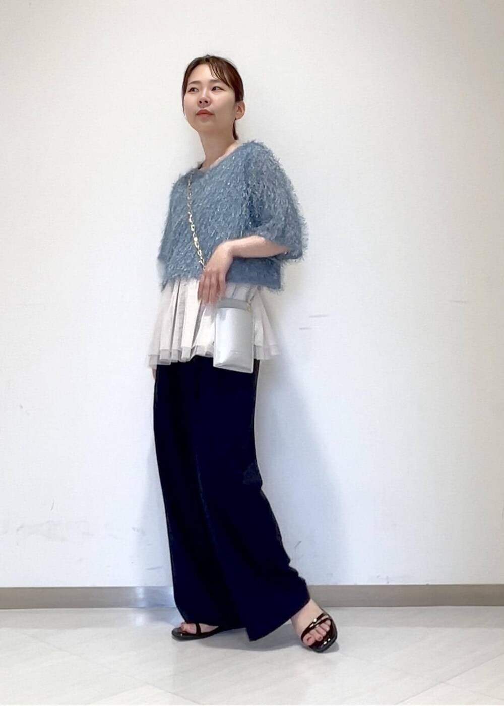 ホワイト系のベスト、ブラック系のサンダル、シルバー系のショルダーバッグを着用したレディースの夏コーディネートの2枚目の写真