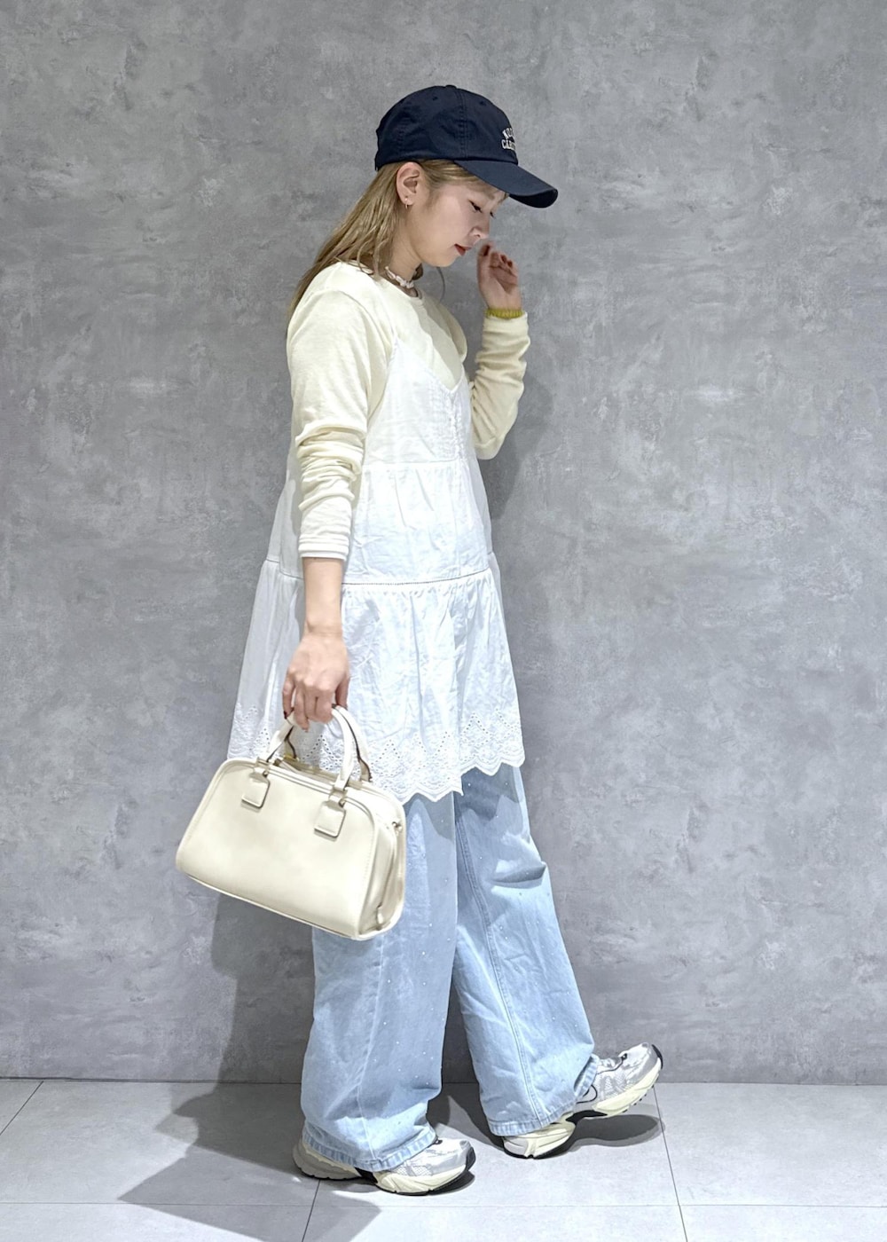 ブルー系のデニムパンツ、ホワイト系のボストンバッグ、ベージュ系のTシャツ/カットソーを着用したレディースの春コーディネートの4枚目の写真