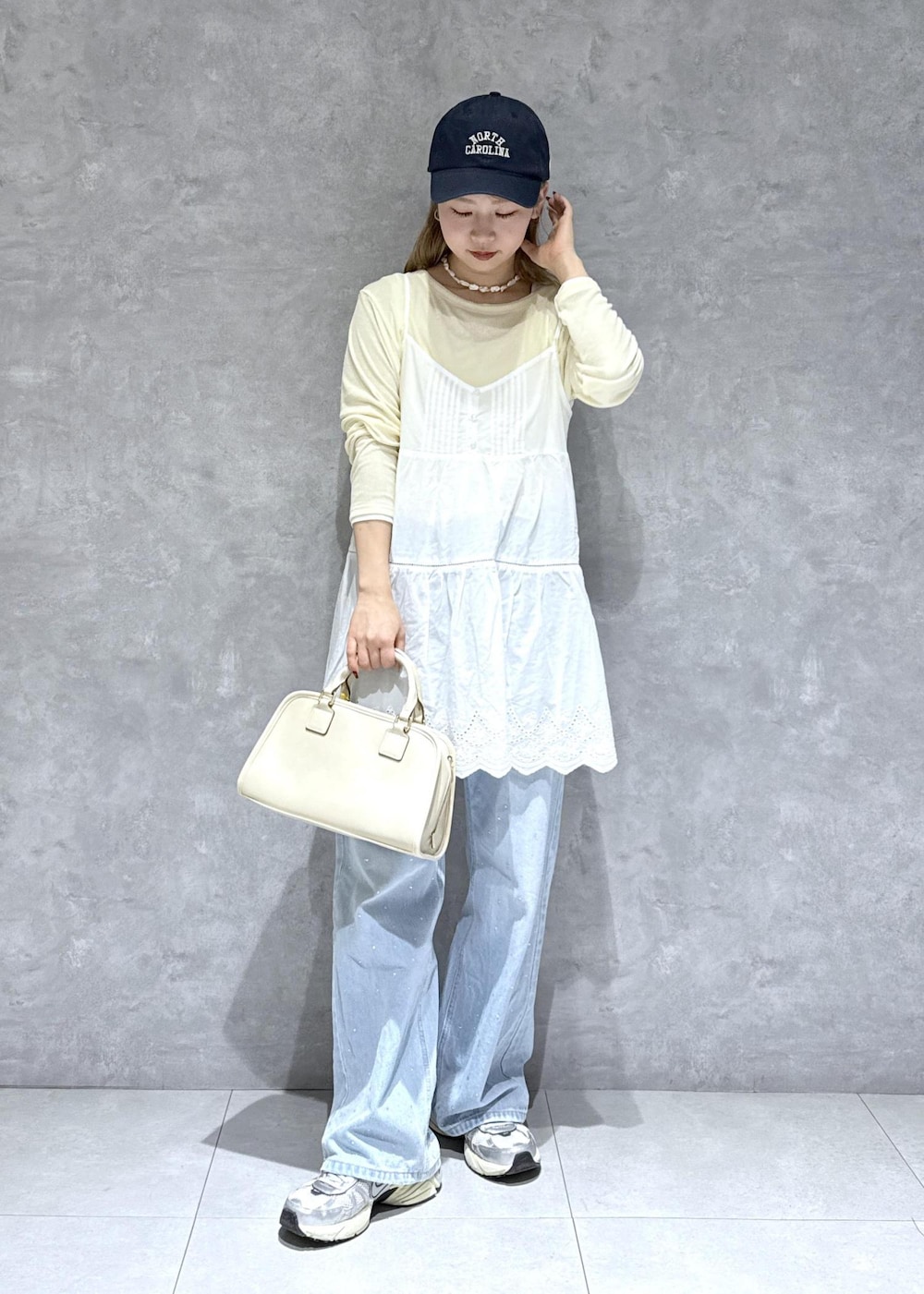 ブルー系のデニムパンツ、ホワイト系のボストンバッグ、ベージュ系のTシャツ/カットソーを着用したレディースの春コーディネートの7枚目の写真