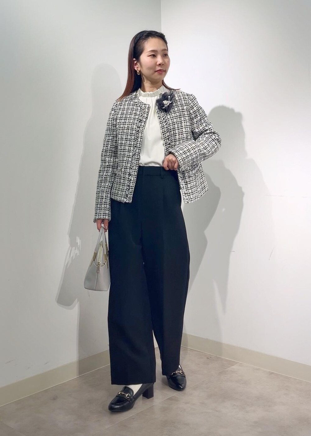 グレー系のショルダーバッグ、ホワイト系のシャツ/ブラウス、ブラック系のノーカラージャケットを着用したレディースの冬コーディネートの2枚目の写真