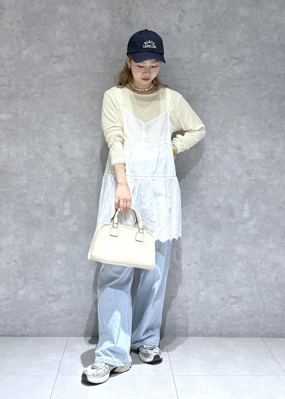 ブルー系のデニムパンツ、ホワイト系のボストンバッグ、ベージュ系のTシャツ/カットソーを着用したレディースの春コーディネートの3枚目の写真