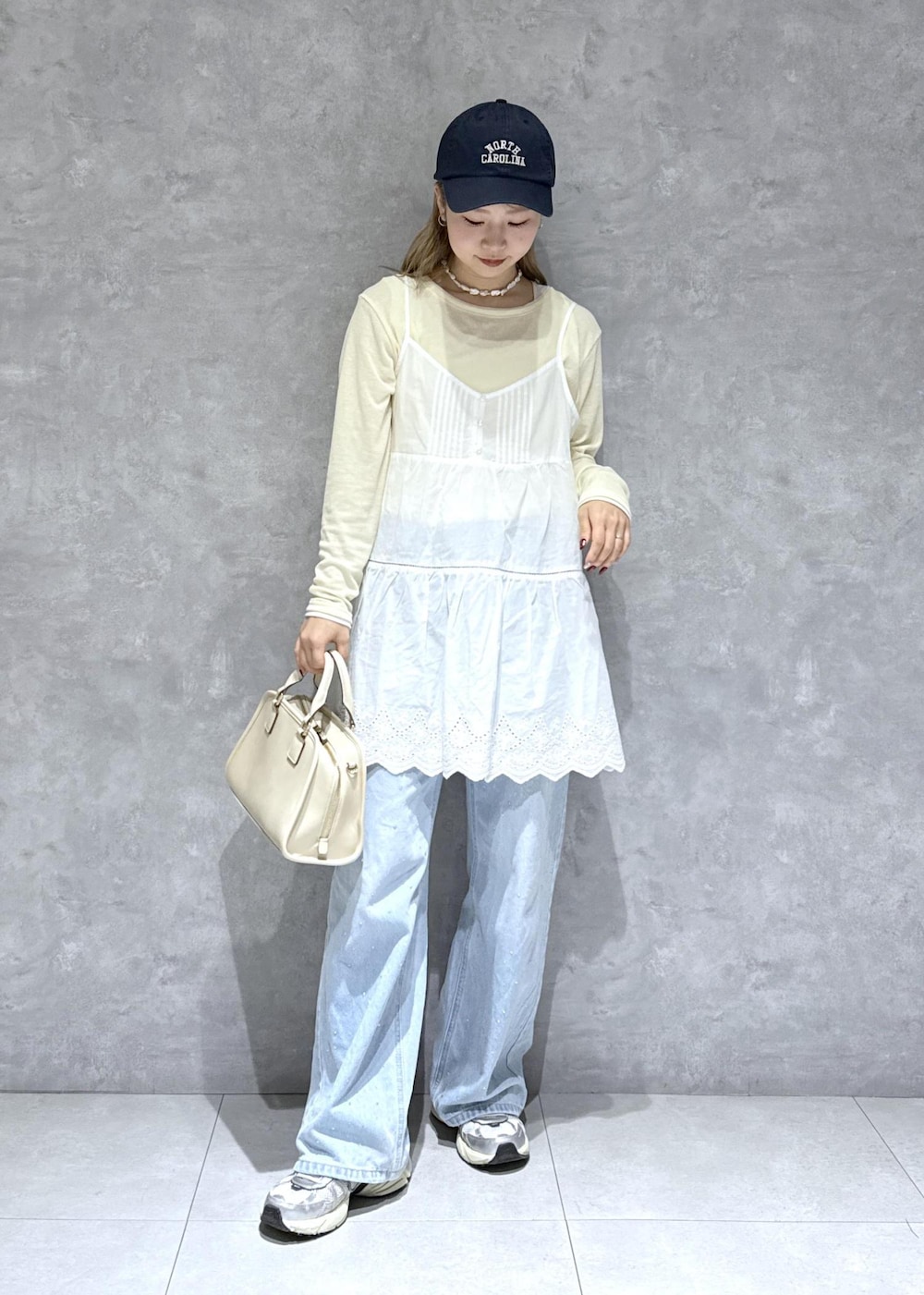 ブルー系のデニムパンツ、ホワイト系のボストンバッグ、ベージュ系のTシャツ/カットソーを着用したレディースの春コーディネートの10枚目の写真