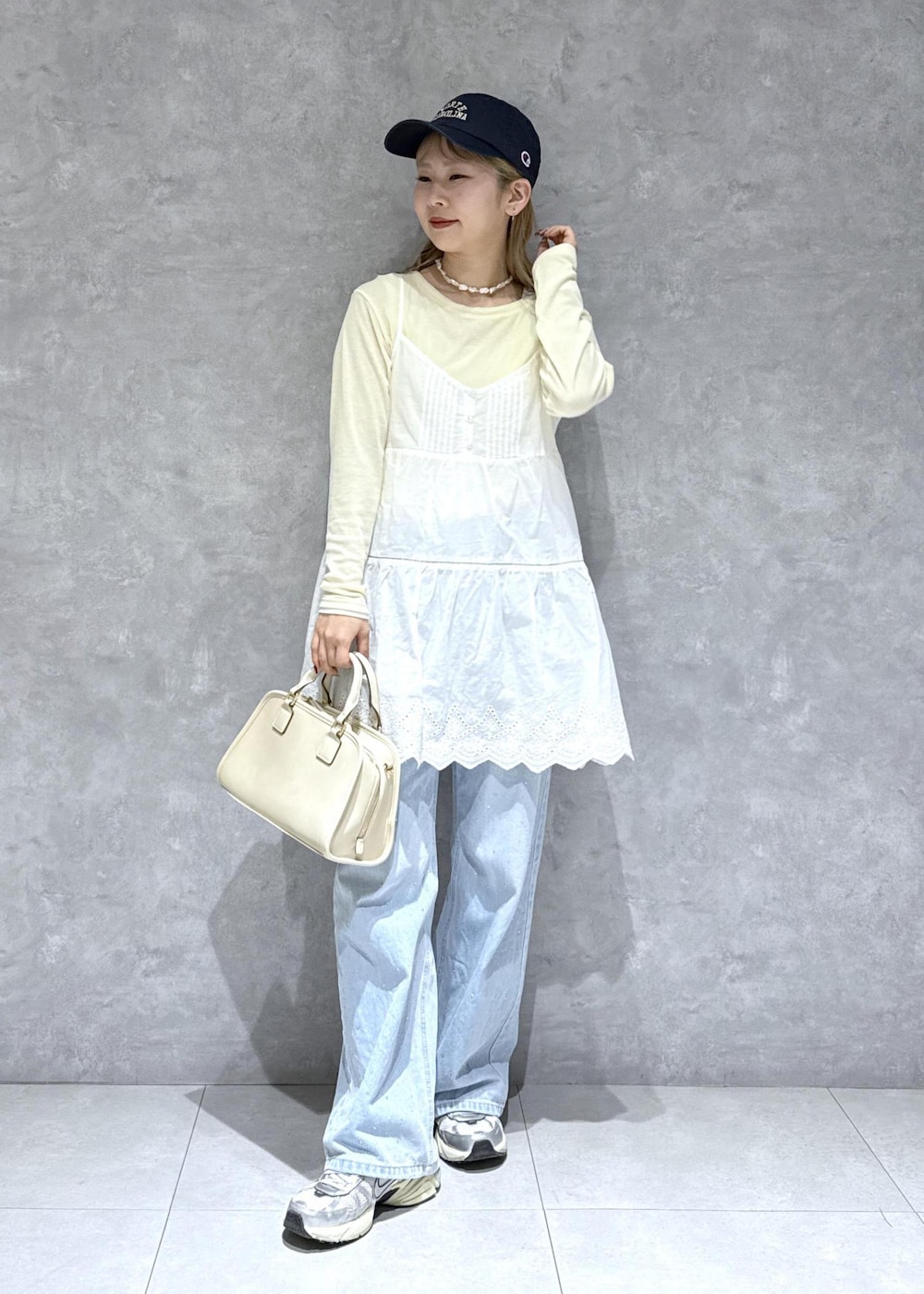 ブルー系のデニムパンツ、ホワイト系のボストンバッグ、ベージュ系のTシャツ/カットソーを着用したレディースの春コーディネートの2枚目の写真