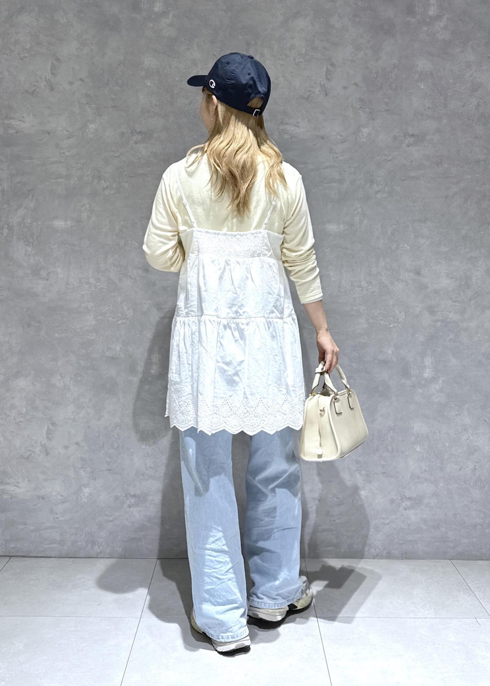 ブルー系のデニムパンツ、ホワイト系のボストンバッグ、ベージュ系のTシャツ/カットソーを着用したレディースの春コーディネートの5枚目の写真