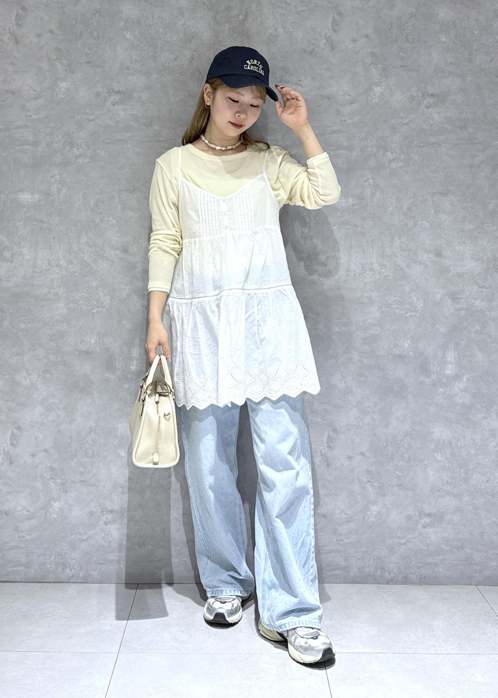 ブルー系のデニムパンツ、ホワイト系のボストンバッグ、ベージュ系のTシャツ/カットソーを着用したレディースの春コーディネートの6枚目の写真