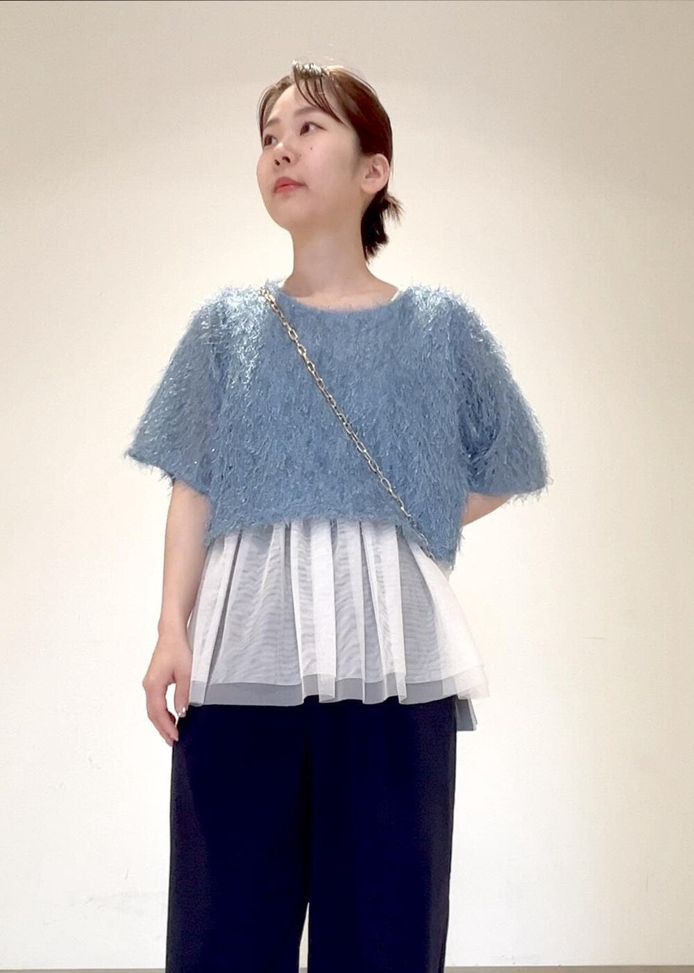 ホワイト系のベスト、ブラック系のサンダル、シルバー系のショルダーバッグを着用したレディースの夏コーディネートの4枚目の写真