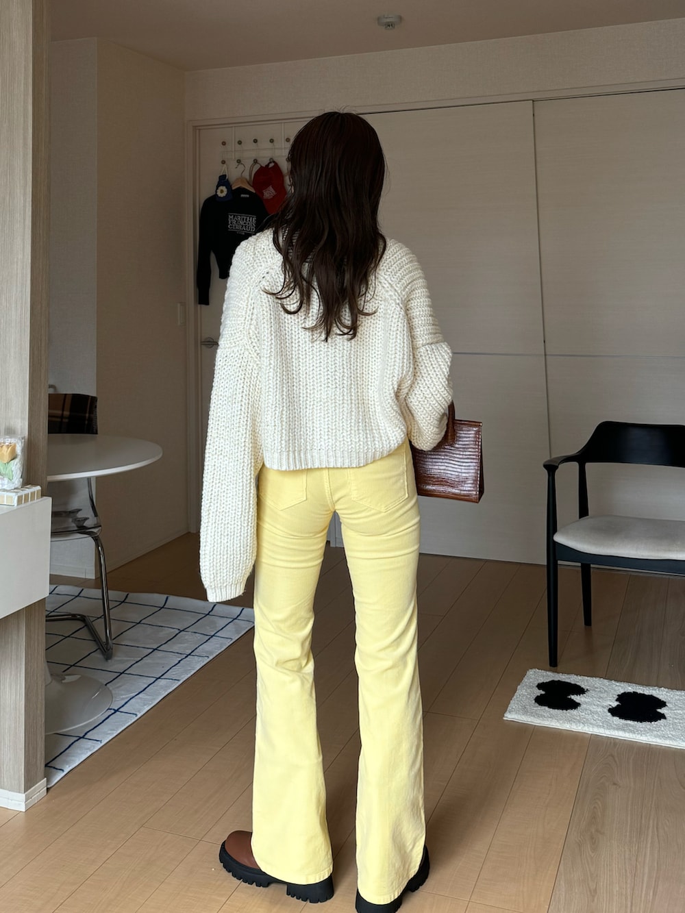 イエロー系のデニムパンツ、ホワイト系のトップス、ベージュ系のTシャツ/カットソーを着用したレディースの冬コーディネートの3枚目の写真