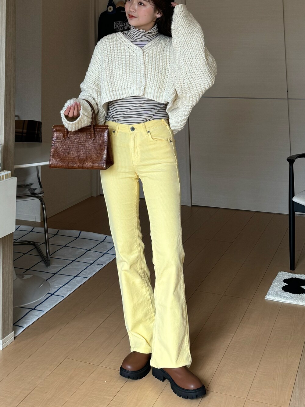 イエロー系のデニムパンツ、ホワイト系のトップス、ベージュ系のTシャツ/カットソーを着用したレディースの冬コーディネートの2枚目の写真