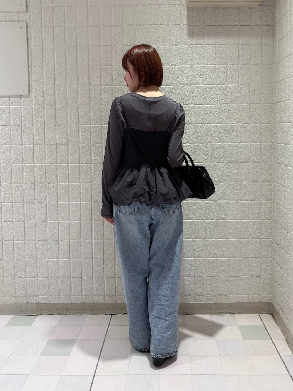 グレー系のTシャツ/カットソー、ブルー系のデニムパンツ、ブラック系のボストンバッグを着用したレディースの冬コーディネートの4枚目の写真