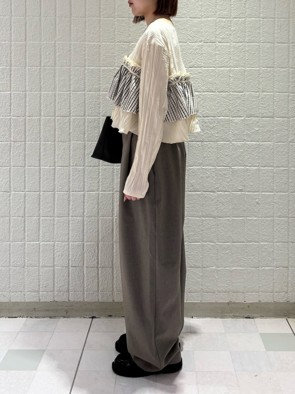 ホワイト系のシャツ/ブラウス、グレー系のその他パンツ、ブラック系のハンドバッグを着用したレディースの春コーディネートの2枚目の写真