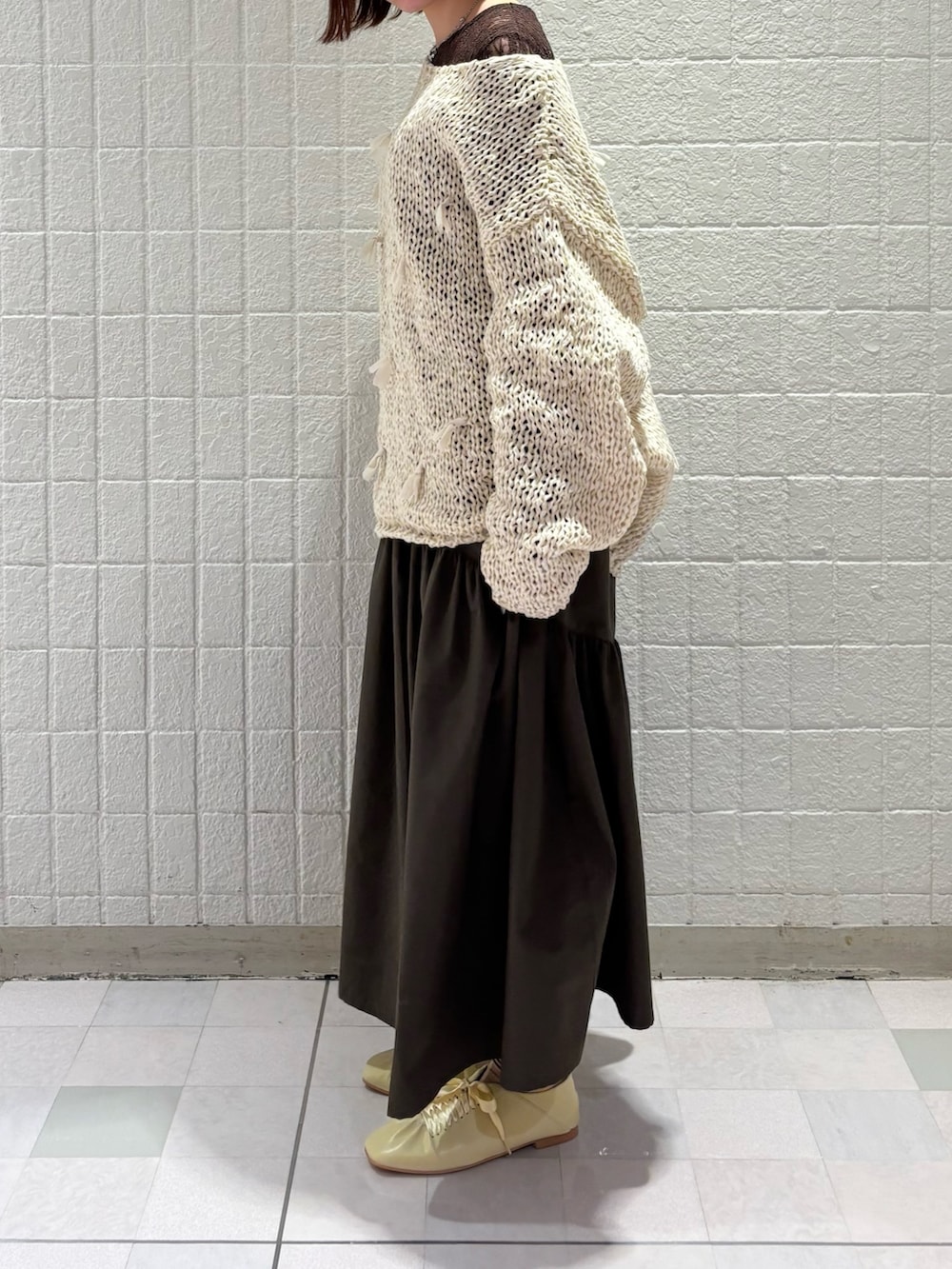 ブラウン系のTシャツ/カットソー、ホワイト系のニット/セーター、グリーン系のスカートを着用したレディースの冬コーディネートの2枚目の写真