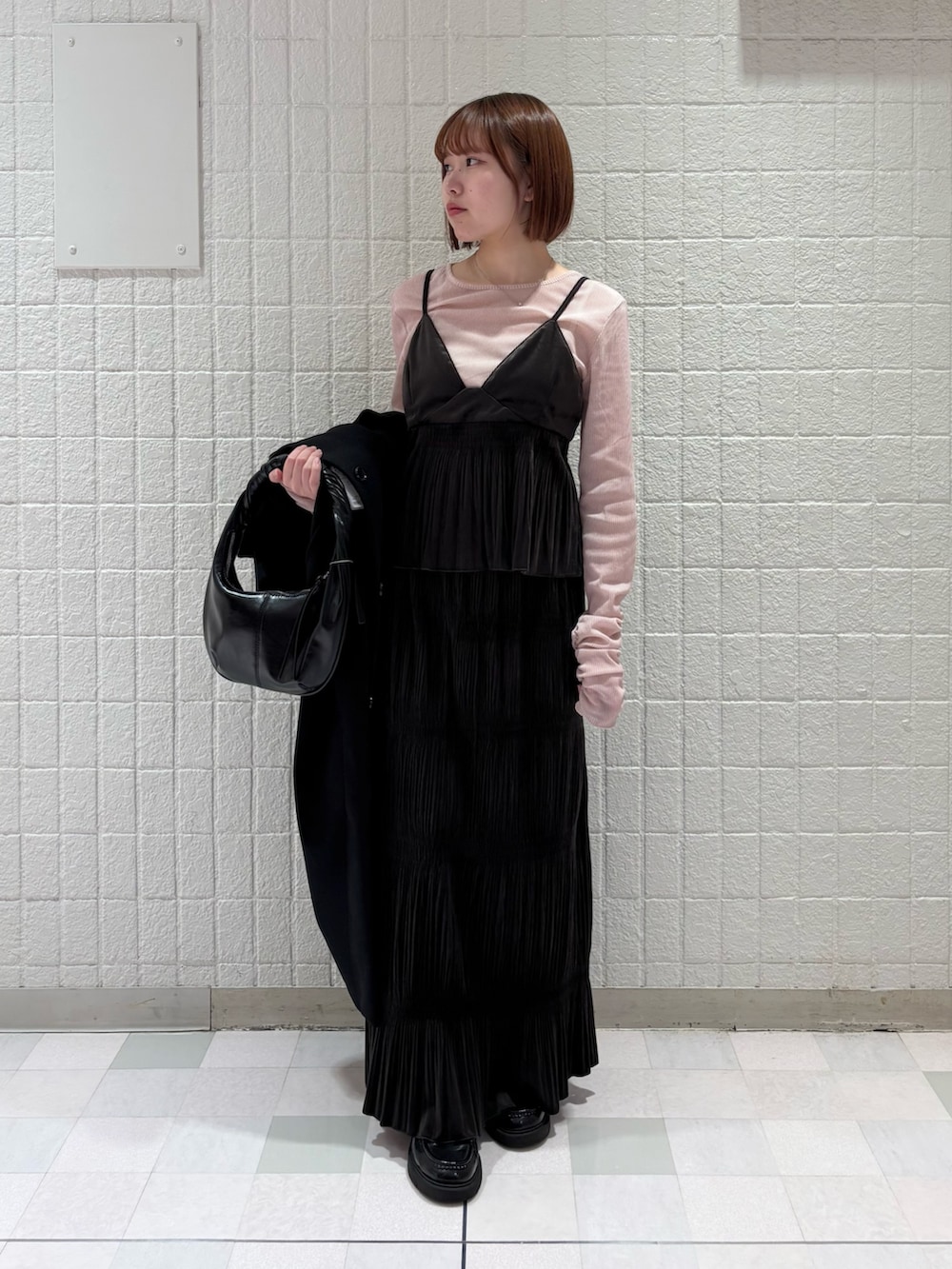 ピンク系のTシャツ/カットソー、ブラック系のステンカラーコート、ブラウン系のワンピースを着用したレディースの冬コーディネートの4枚目の写真